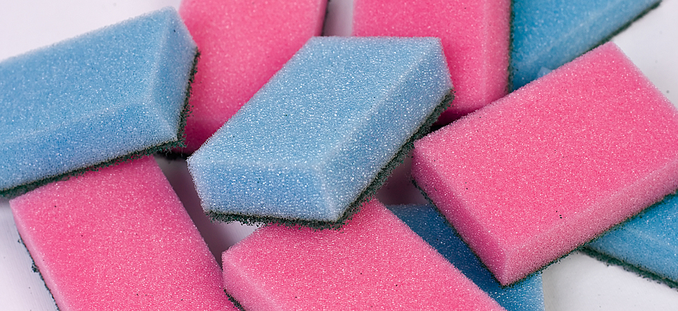 A pile of simple polyurethane sponges, commonly used in the kitchen for cleaning dirty dishes. They have either a blue or pink porous side and another green, more abrasive one similar in texture to nap.